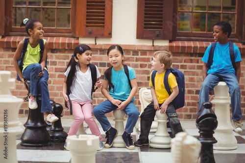 Happy pupils sitting on giant chess pieces