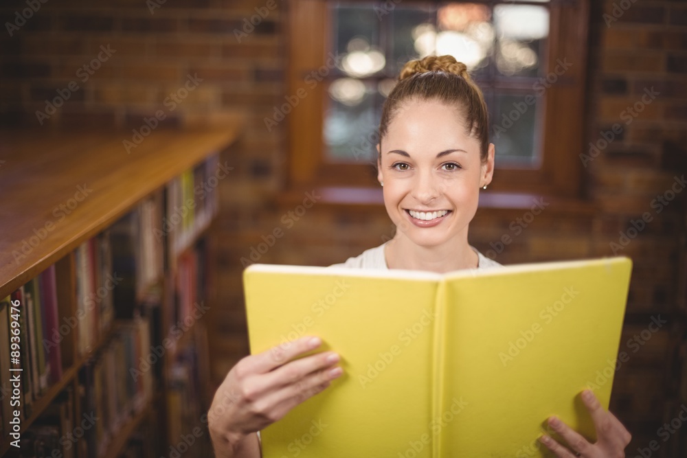 Blonde teacher reading book in the library Blonde teacher reading book in the library