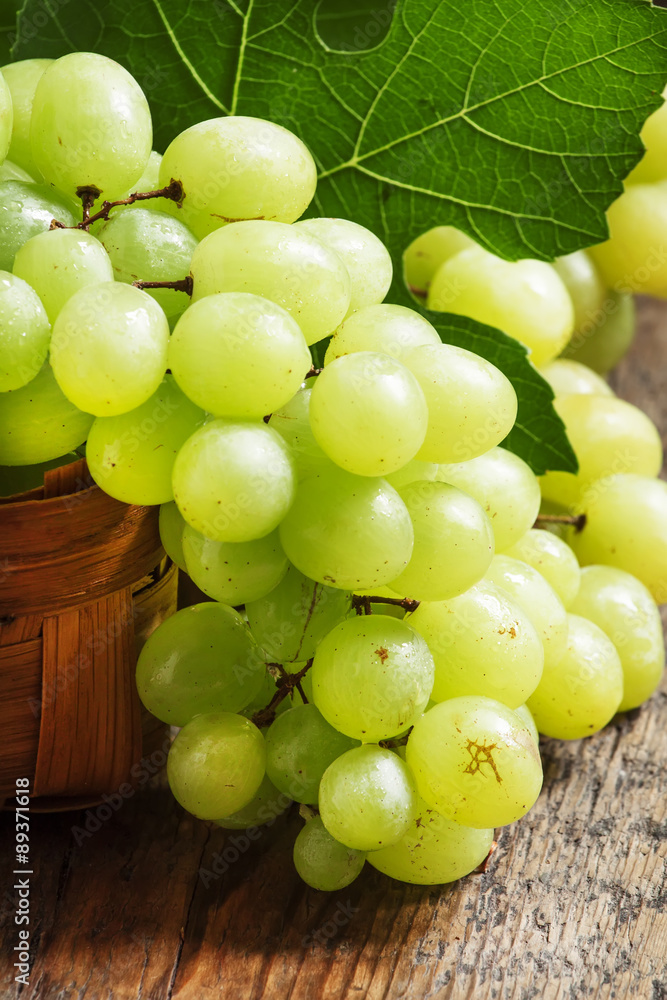 Green grapes in a wicker basket in a rustic style, selective foc Green grapes in a wicker basket in a rustic style, selective foc