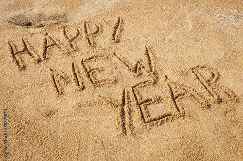The words Happy New Year written in the sand on the beach