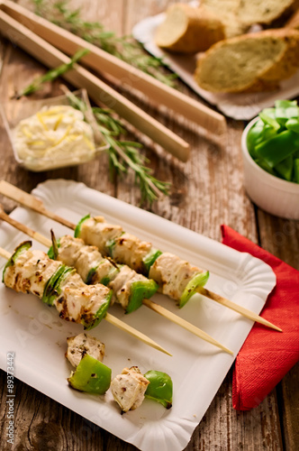 Concept of outdoor barbecue picnic food. Chicken and peppers shish-kebabs or souvlaki on skewers on a rustic wood table