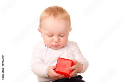 baby boy in white playing with toy red block