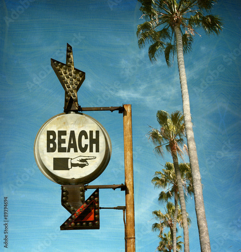 aged and worn vintage photo of beach sign with palm trees