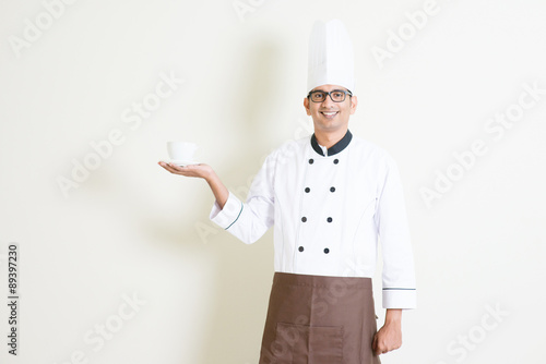 Indian male chef in uniform presenting a coffee cup