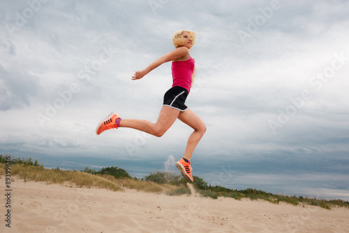 Jumping blond woman in summer sportswear.