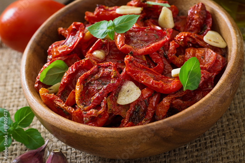 Sun-dried tomatoes with herbs and garlic in wooden bowl