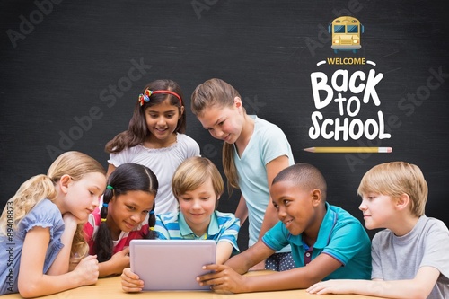 Composite image of cute pupils using tablet computer in library 
