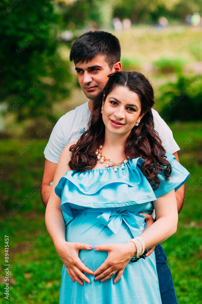 Fototapeta premium Beautiful pregnant couple relaxing outside in the park.