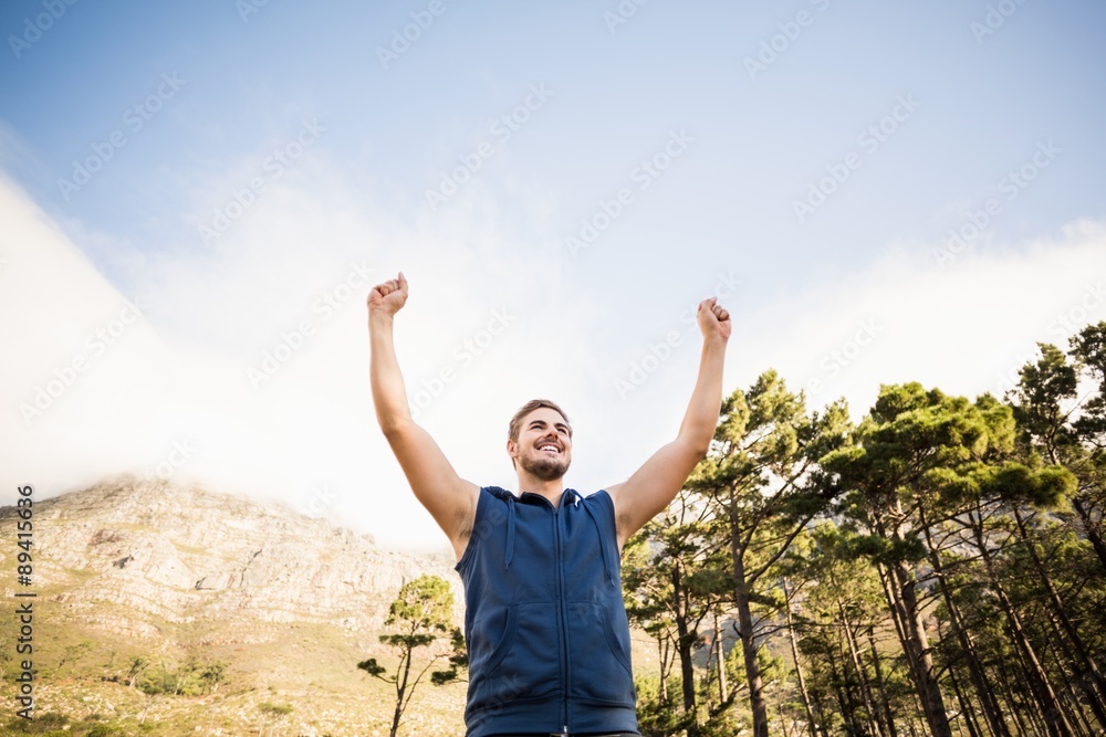 Young happy jogger standing on rock and cheering Young happy jogger standing on rock and cheering