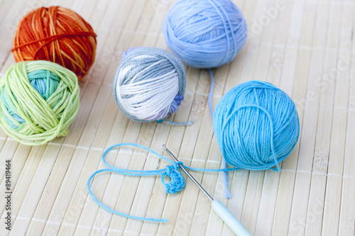 Colorful clews and crochet hook on wooden background