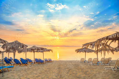 Fototapeta Naklejka Na Ścianę i Meble -  Vivid sunrise on a beautiful sandy beach with sunshade