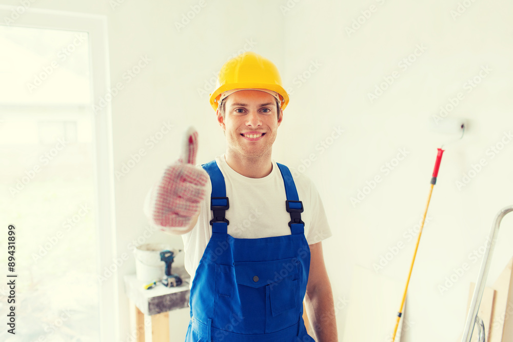 smiling young builder in hardhat showing thumbs up smiling young builder in hardhat showing thumbs up