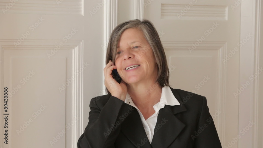 businesswoman in her 50s talking on the phone and looks cheerful businesswoman in her 50s talking on the phone and looks cheerful