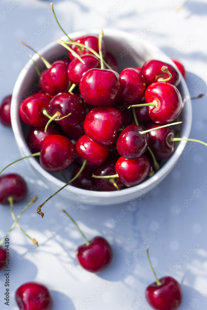 Sweet cherries in the bowl, on the garden table.