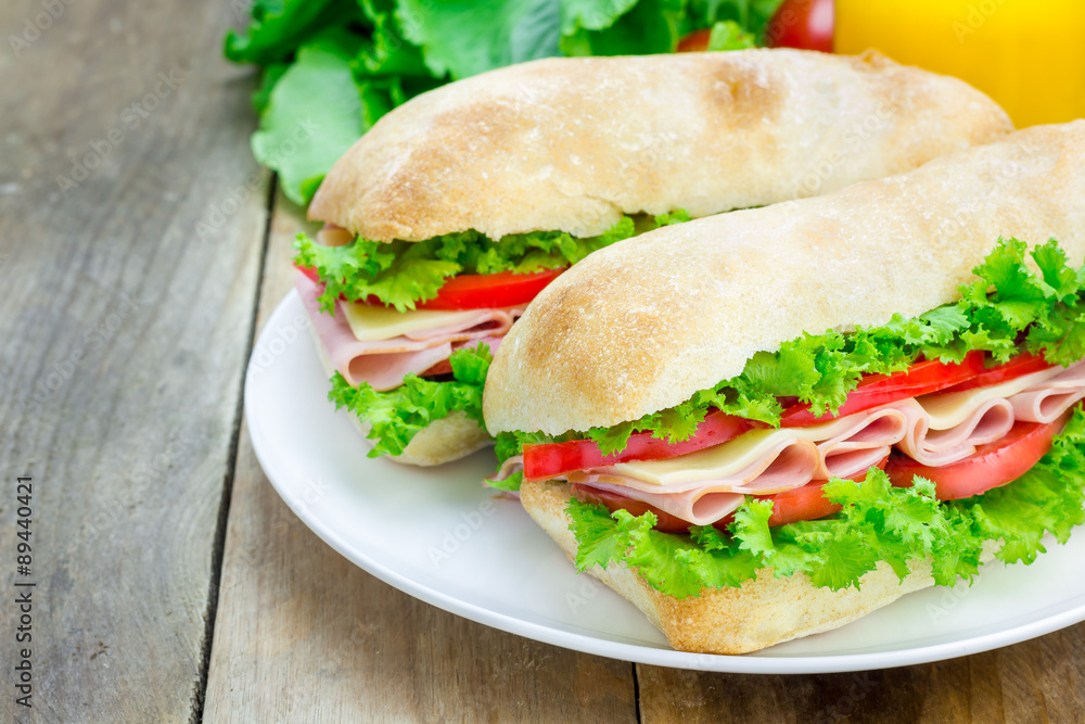 Healthy ciabatta bread sandwiches with ham and cheese on the white plate Healthy ciabatta bread sandwiches with ham and cheese on the white plate