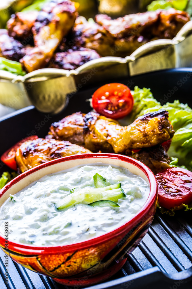 Tzatziki sauce. Tzatziki dressing. Tzatziki dressing with grilled chicken legs and fresh vegetable,lettuce leaf and cherry tomatoes. Grilled chicken legs, lettuce and tomatoes. Mediterranean cuisine.