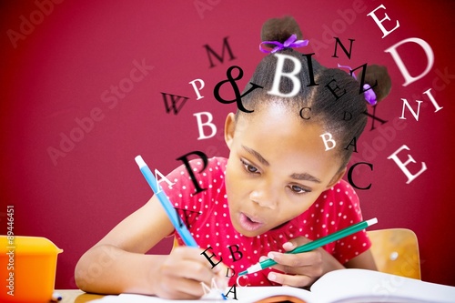 Composite image of cute pupil writing at desk in classroom photo