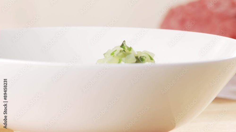 Fried onion and parsley mixture being placed on a plate Fried onion and parsley mixture being placed on a plate