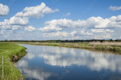 Quiet river, clouds reflected in the calm water.