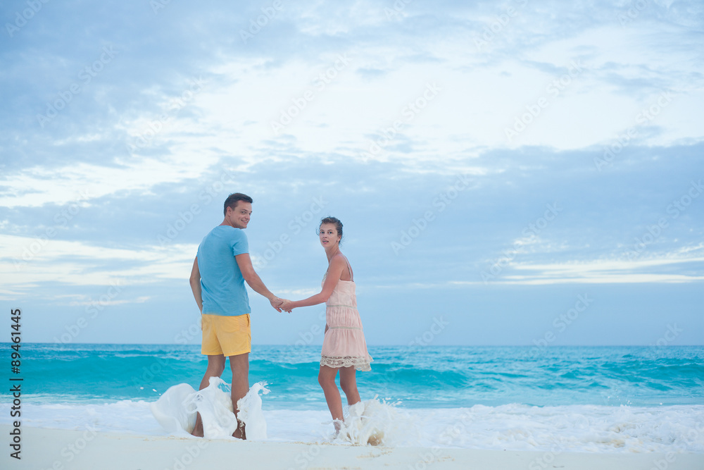 Back view of couple in bright clothes having fun at tropical Back view of couple in bright clothes having fun at tropical