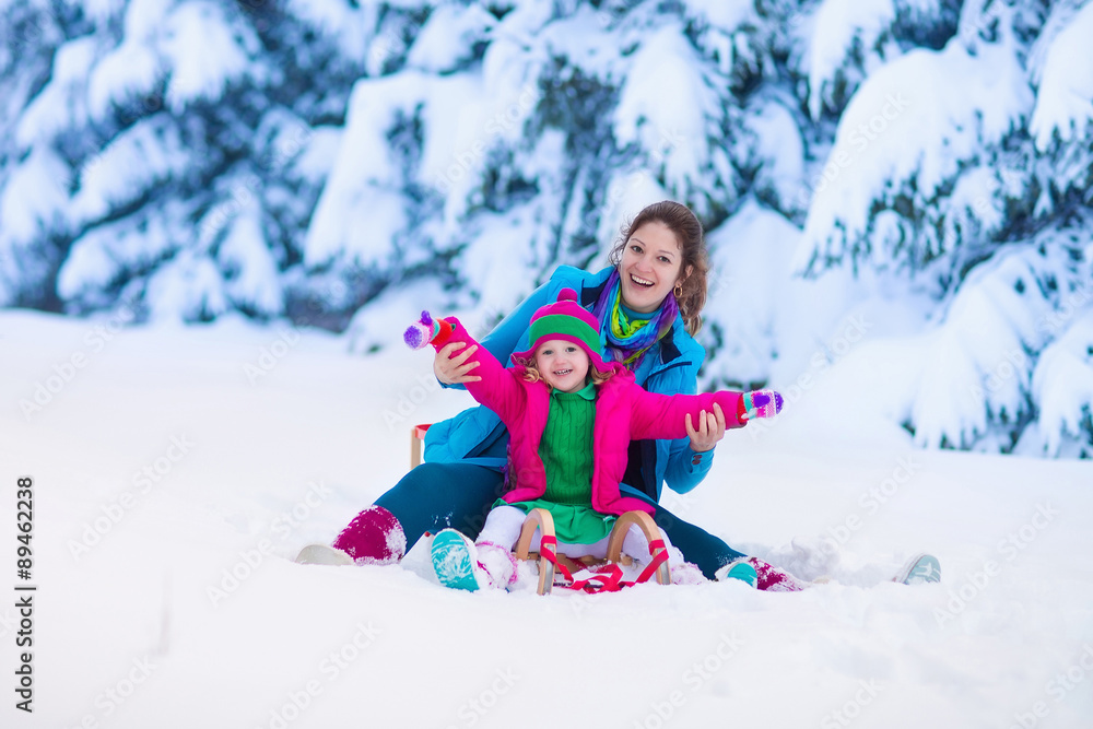Mother and child sledding in a snowy park Mother and child sledding in a snowy park