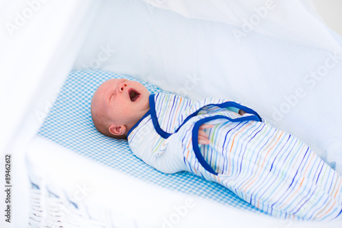 Little swaddled baby in white bed photo