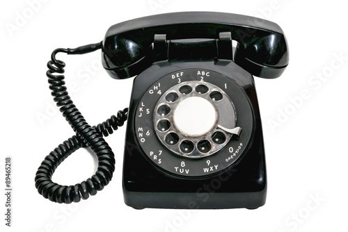 Old black vintage rotary dial telephone on white background