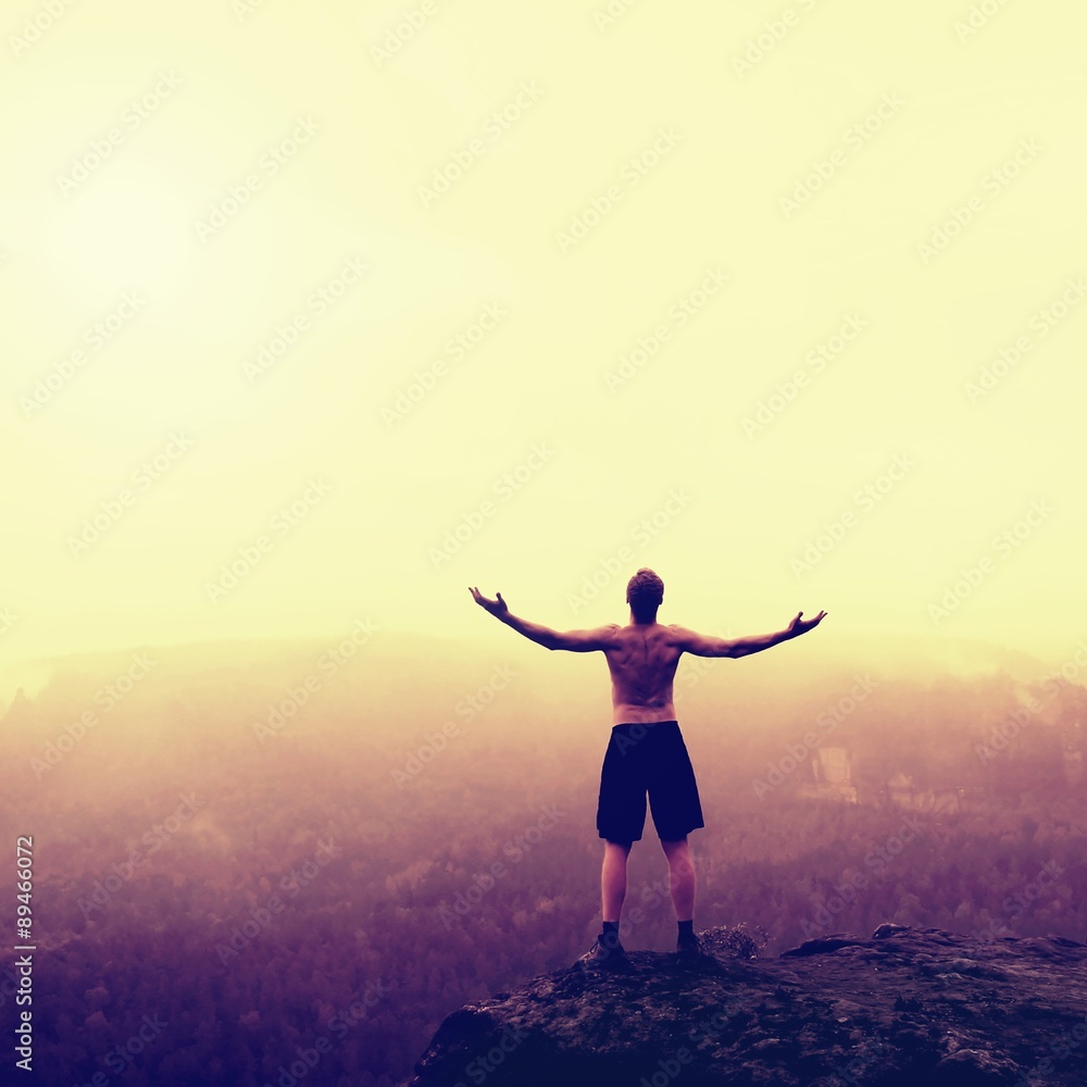 Gesture of triumph.. Climber in black pants. Naked tourist on the peak of sandstone rock in national park Saxony Switzerland watching into misty landscape.