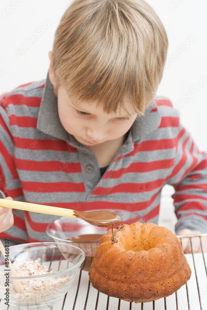 Little boy decorating ring cake with chocolate icing Little boy decorating ring cake with chocolate icing