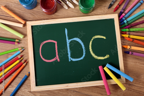 ABC written on a small blackboard on a child student desk with crayons and pencils basic alphabet learning reading writing photo photo