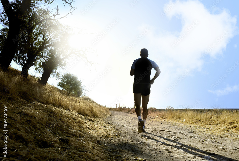 Silhouette sport man running on countryside in cross country at summer sunset