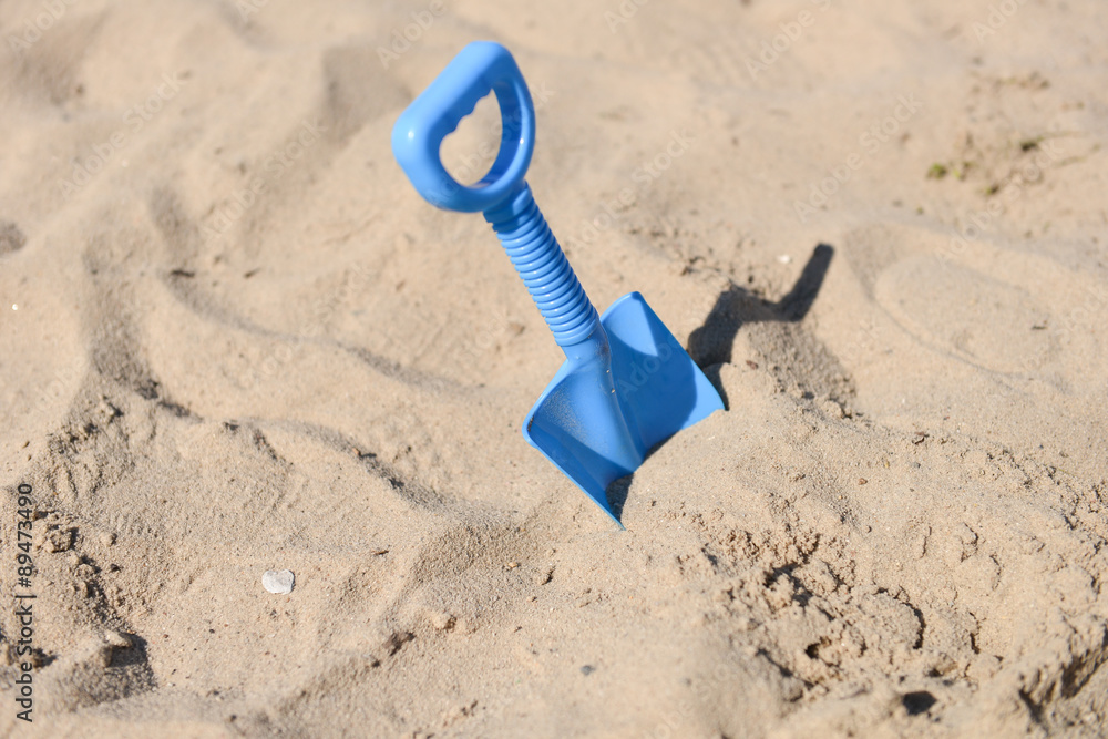 blue beach shovel stuck in the sand by a child blue beach shovel stuck in the sand by a child
