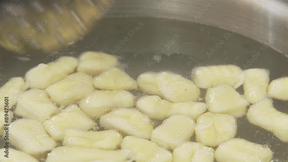 Gnocci being removed from salt water with a draining spoon Gnocci being removed from salt water with a draining spoon