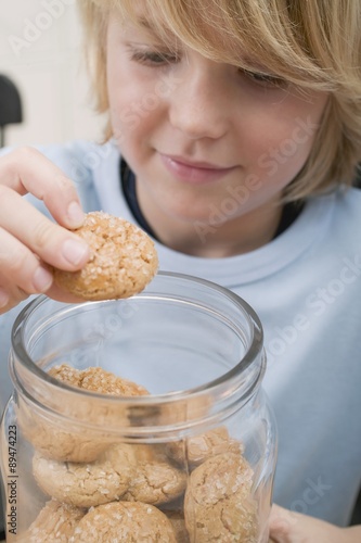 Boy taking biscuit out of storage jar