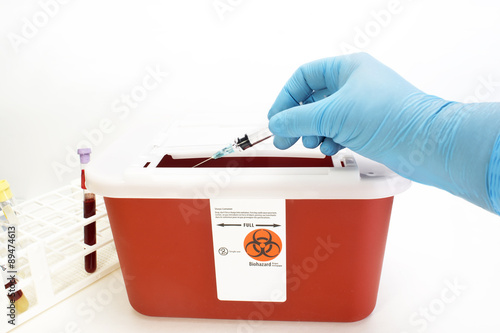 Technician drops syringe into sharps container.