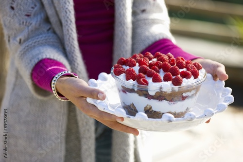 Woman holding a glass bowl of raspberry trifle