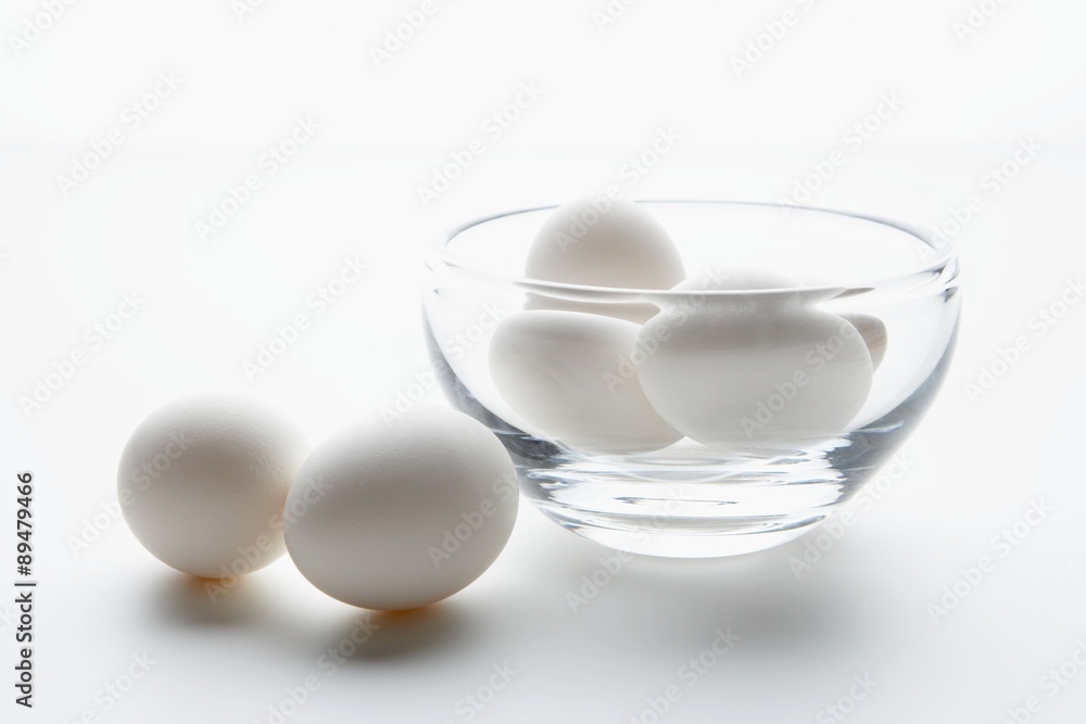 White eggs in and beside a glass bowl White eggs in and beside a glass bowl