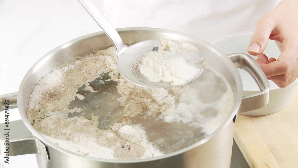 Foam being scooped off the top of beef stock Foam being scooped off the top of beef stock