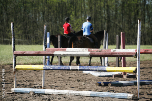 Unknown riders on a horse jumping training summertime outdoor