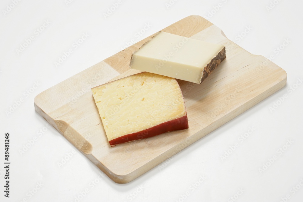 Two raw milk cheeses on wooden board Two raw milk cheeses on wooden board