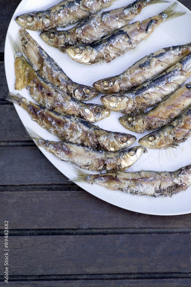 Grilled sardines on white platter Grilled sardines on white platter
