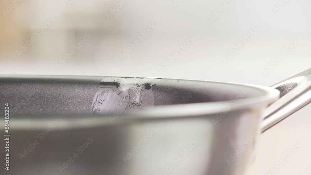 A piece of butter being placed in a pan A piece of butter being placed in a pan