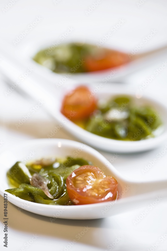 Cocktail tomatoes with anchovies and green pepper in spoons Cocktail tomatoes with anchovies and green pepper in spoons