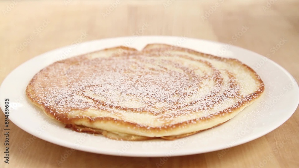Pancakes being dusted with icing sugar Pancakes being dusted with icing sugar