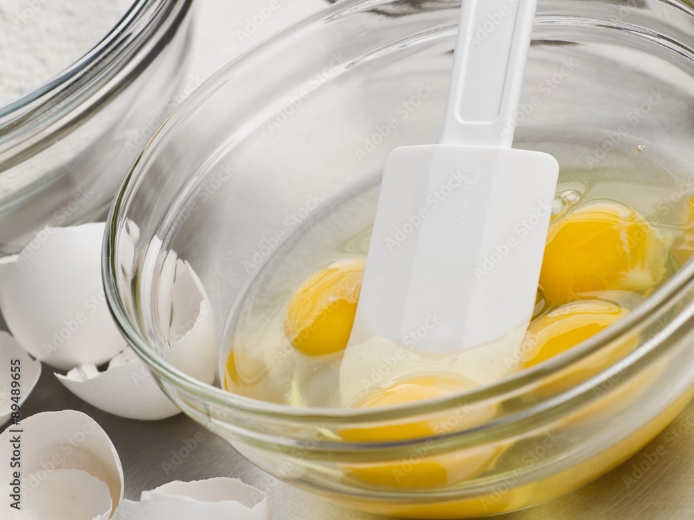 Cracked Eggs in a Mixing Bowl with a Rubber Spatula Cracked Eggs in a Mixing Bowl with a Rubber Spatula