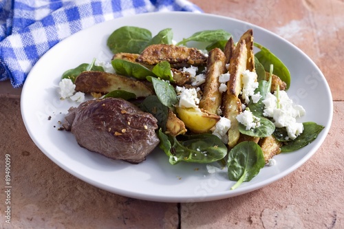 Lamb fillet on a warm potato salad with spinach and feta cheese photo