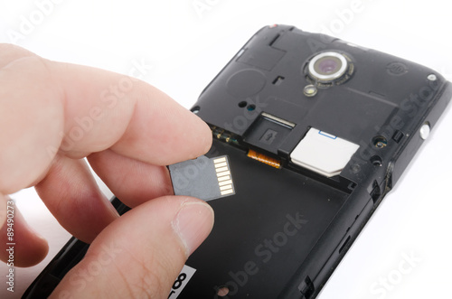 Human hand inserting Micro SD card into cell phone (smartphone)
