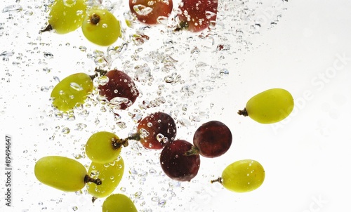 Fototapeta Naklejka Na Ścianę i Meble -  Red and green grapes falling into water