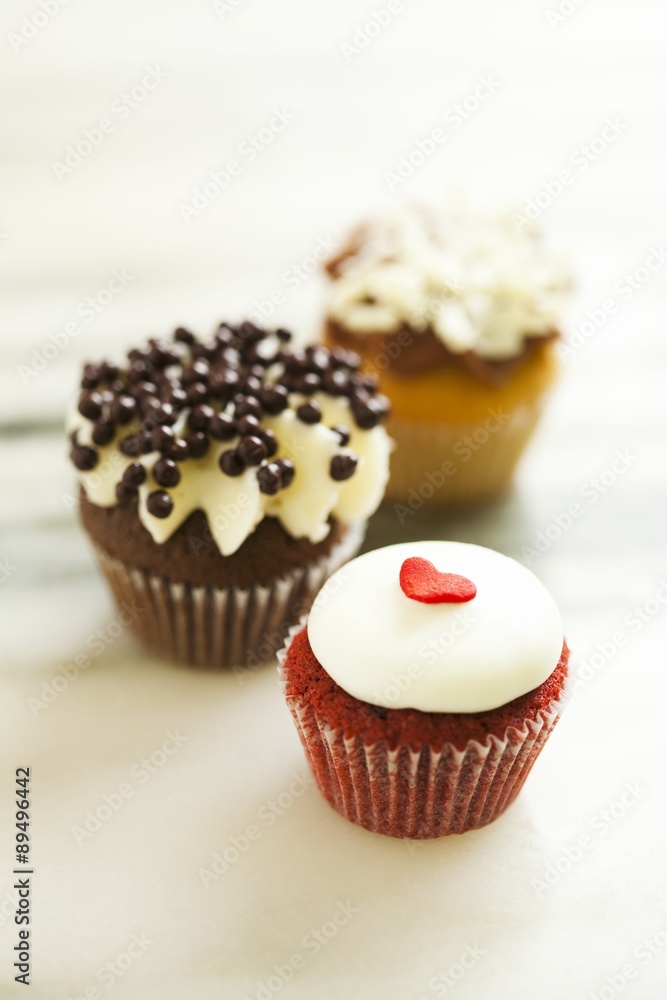 Three Assorted Decorated Cupcakes; On Marble