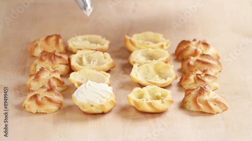 Profiteroles being filled with cream